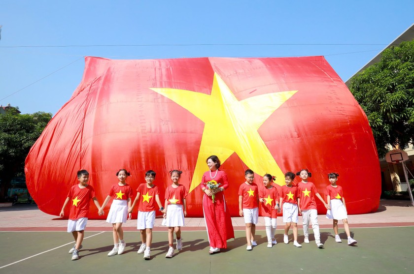 Cô giáo Nguyễn Thanh Huyền - Bí thư chi bộ - Hiệu trưởng cùng các em học sinh trên sân trường.